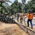 Pasukan Gabungan TNI terlihat membangun jembatan sementara yang rusak akibat banjir bandang di Labura, kemarin.