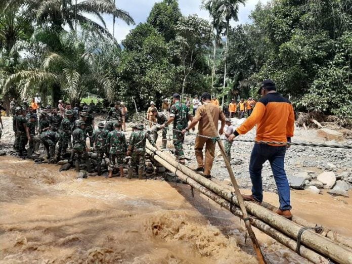 Pasukan Gabungan TNI terlihat membangun jembatan sementara yang rusak akibat banjir bandang di Labura, kemarin.