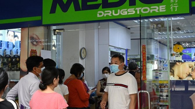 Warga mengantri di luar apotek untuk membeli masker, termometer, dan pembersih tangan di Singapura (29/1/2020). Singapura sejauh ini mengonfirmasi tujuh kasus virus corona (coronavirus) - semuanya datang dari Wuhan. (AFP Photo/Roslan Rahman)