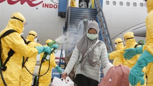 Petugas medis menyemprotkan cairan disinfektan pada Warga Negara Indonesia (WNI) dari Wuhan, China setibanya di Bandara Hang Nadim, Batam, Kepulauan Riau, Minggu (2/2/2020). (ANTARA FOTO/Kementerian Luar Negeri RI/mrh/aww)