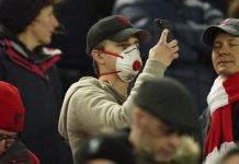 Fans Liverpool menggunakan masker saat menyaksikan laga di Anfield Stadium.(sumber: CNN)