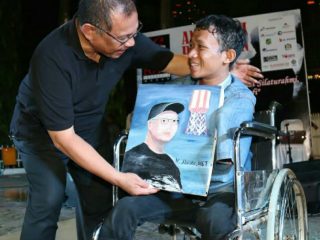 Plt Walikota Medan, Akhyar Nasution saat menerima lukisan wajahnya dari Prayoga di sela - sela HUT PFI Kota Medan di Merdeka Walk, Jumat malam (13/3/2020)