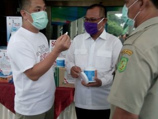 Perwakilan Capital Group, Romi menunjukkan tablet disinfektan yang merupakan bantuan mereka kepada Plt Walikota Medan, Akhyar Nasution di Halaman Kantor Walikota Medan, Selasa (14/4/2020)
