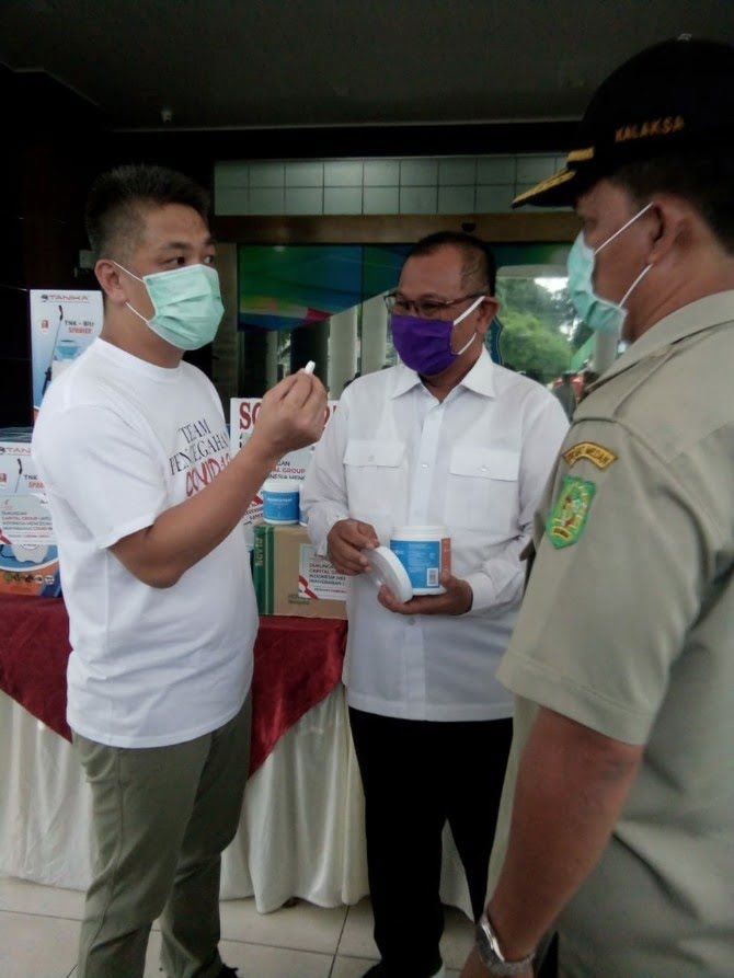Perwakilan Capital Group, Romi menunjukkan tablet disinfektan yang merupakan bantuan mereka kepada Plt Walikota Medan, Akhyar Nasution di Halaman Kantor Walikota Medan, Selasa (14/4/2020)