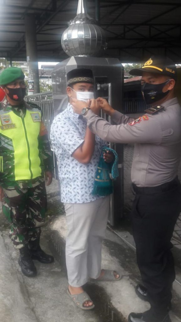 Salah seorang siswa Stukpa yang mengikuti latihan kerja di Polsek Siantar Martoba, Franky M Chandra Ritonga memakaikan masker kepada warga yang akan beribadah di masjid, Jumat (11/9/2020).