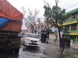 Seorang warga berjalan di genangan banjir di Jalan Marelan Raya, Sabtu (26/12/2020). Warga berharap walikota medan punya solusi untuk banjir di sana.(mustivan/kaldera)