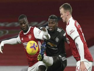 Gelandang MU, Paul Pogba dijepit pemain Arsenal. Laga ini berakhir imbang tanpa gol.