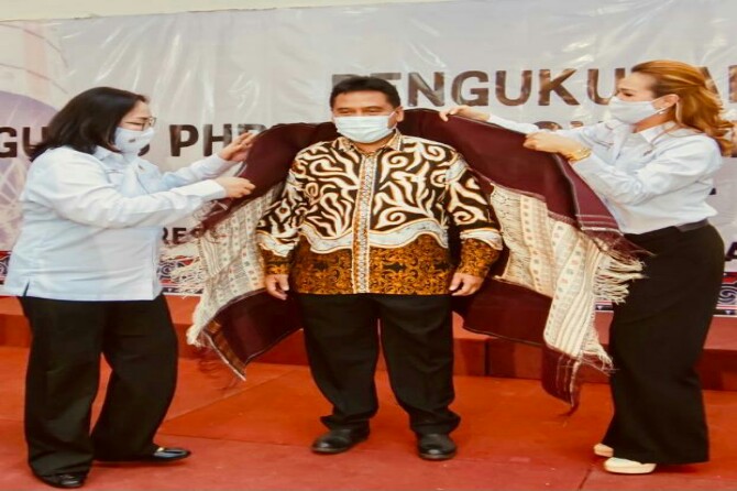 Dewi Juita Purba (kiri) dan Eva Christina Ginting (kanan) memakaikan ulos kepada Ketua BPP PHRI Hariyadi Sukamdani, Sabtu lalu.