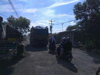 Dump truk pengangkut material galian C tampak melintasi jalan rusak di Jalan Pertahanan, Dusun VI, Desa Patumbak Kampung.