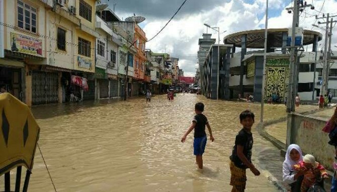 Sejumlah anak bermain di tengah banjir akibat meluapnya Sungai Padang, Tebing Tinggi.