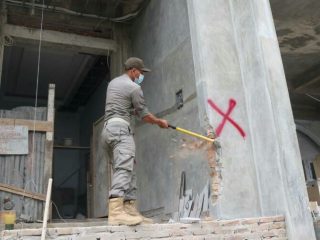 Salah seorang personel Satpol PP Kota Medan sedang menghancurkan dinding bangunan rumah mewah yang menyalahi izin di Jalan Katelia Kecamatan Medan Helvetia, Selasa (22/2/2022). Foto:ist