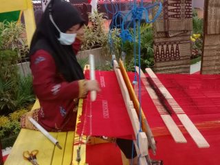 Salah seorang ibu sedang menenun kain ulos di rangkaian acara APEKSI 2022 di Gedung PKK Kota Medan, Jalan Rotan Medan, Kamis (30/6/2022)