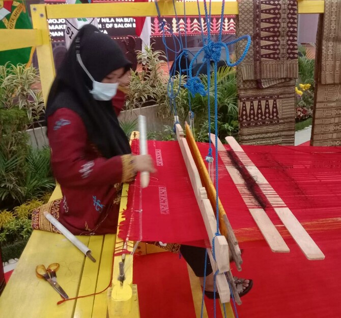 Salah seorang ibu sedang menenun kain ulos di rangkaian acara APEKSI 2022 di Gedung PKK Kota Medan, Jalan Rotan Medan, Kamis (30/6/2022)
