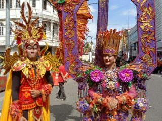 Dua orang muda mudi peserta karnaval budaya melintas di Jalan Ahmad Yani, Medan, Jumat (1/7/2022)
