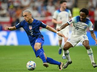 Pemain Amerika Serikat berusaha melakukan penyerangan ke arah pertahanan Inggris. Kedua tim bermain imbang 0-0