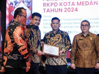 Walikota Medan, Bobby Afif Nasution menyerahkan penghargaan kepada Sekretaris DPRD Medan, Ali Sipahutar dalam lomba inovasi pelayanan publik Kota Medan, Kamis (16/3/2023). Foto:Dinas Kominfo Kota Medan