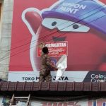 Personel Satpol PP Kota Medan menempelkan stiker tanda tidak bayar pajak di salah satu reklame merek toko di Kota Medan