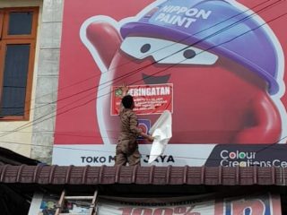 Personel Satpol PP Kota Medan menempelkan stiker tanda tidak bayar pajak di salah satu reklame merek toko di Kota Medan