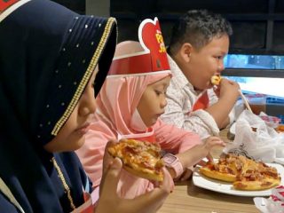 Sejumlah anak yatim sedang menikmati pizza