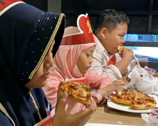 Sejumlah anak yatim sedang menikmati pizza