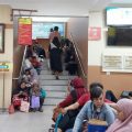 Warga yang mengurus administrasi kependudukan harus duduk di tangga akses ke lantai atas saat menunggu antrian.