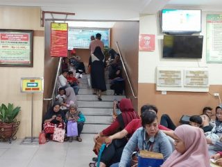 Warga yang mengurus administrasi kependudukan harus duduk di tangga akses ke lantai atas saat menunggu antrian.