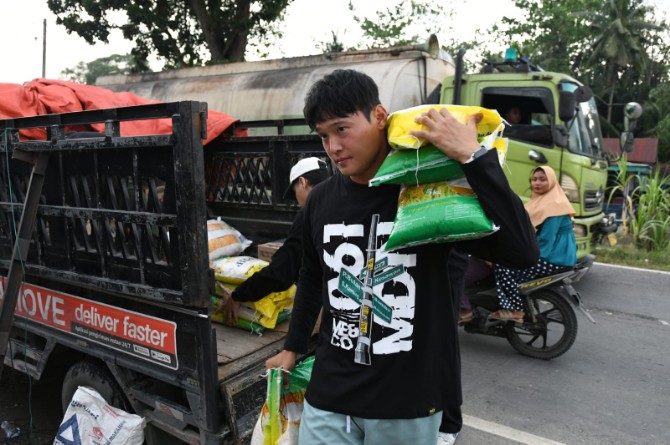 Pemain Asing PSMS Medan asal Korea Selatan, Kim membawa beras untuk diberikan kepada warga korban banjir di Langkat, Jumat (12/12/2025). Foto; IST