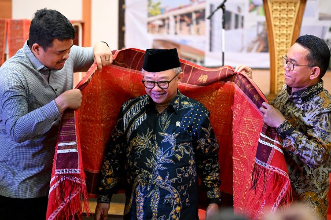 Teks Poto; Gubernur Sumatera Utara Bobby Afif Nasution bersama Wakil Wali Kota Medan Zakiyuddin Harahap memakaikan ulos (kain khas adat Batak) ke Menteri Pendidikan Dasar dan Menengah RI, Abdul Mu'ti. Foto; dokumen Dinas Kominfo Kota Medan